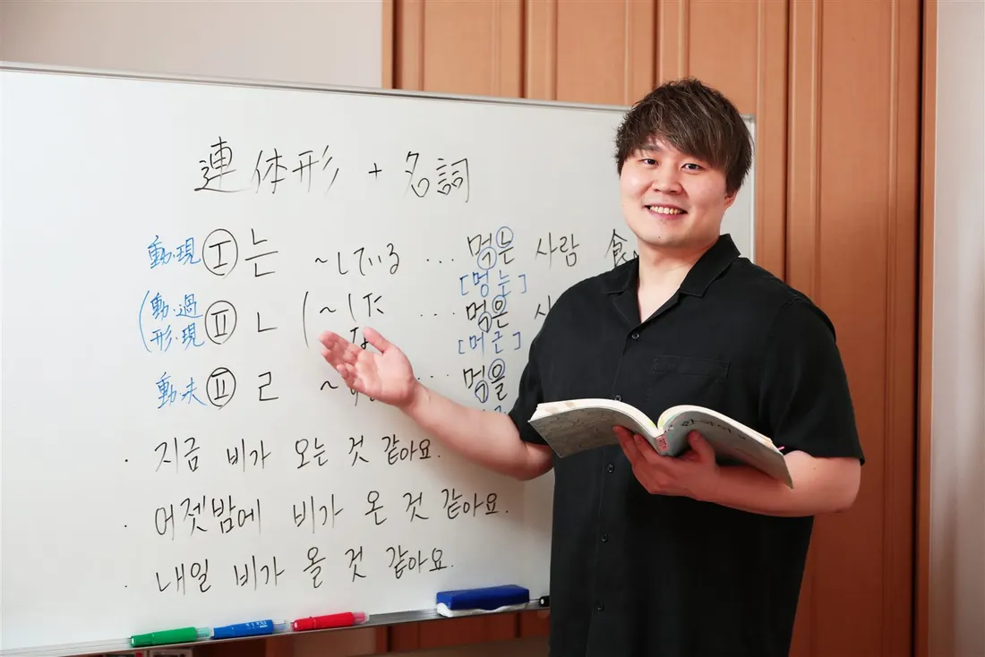 ホワイトボードの前で、語基式の文法を説明する講師